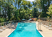Thumbnail 16 of 20 - A large swimming pool surrounded by trees and chairs.