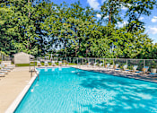 Thumbnail 15 of 20 - A large outdoor swimming pool surrounded by trees and lounge chairs.