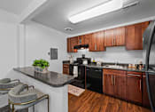 Thumbnail 1 of 20 - A kitchen with a black stove top oven and wooden cabinets.