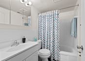Thumbnail 8 of 20 - A white bathroom with a blue and white shower curtain.