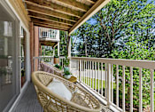 Thumbnail 9 of 20 - A wicker chair is on a porch with a view of trees.