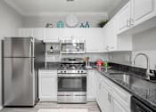 Thumbnail 14 of 42 - A modern kitchen with white cabinets and stainless steel appliances at The Grand Reserve at Tampa Palms Apartments, Tampa, 33647