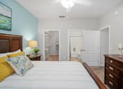 Thumbnail 24 of 42 - A bedroom with a bed, dresser, and a painting on the wall at The Grand Reserve at Tampa Palms Apartments, Tampa, 33647