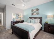 Thumbnail 21 of 42 - A bedroom with a bed, nightstands, and a ceiling fan at The Grand Reserve at Tampa Palms Apartments, Tampa, FL, 33647