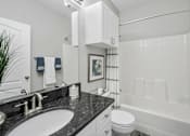 Thumbnail 12 of 42 - A bathroom with a white tub, sink, and toilet at The Grand Reserve at Tampa Palms Apartments, Florida