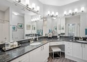 Thumbnail 9 of 42 - A bathroom with white vanity, black counters and large mirrors at The Grand Reserve at Tampa Palms Apartments, Tampa, 33647