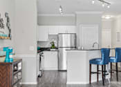 Thumbnail 2 of 42 - A kitchen with a refrigerator, sink, and two blue barstools at The Grand Reserve at Tampa Palms Apartments, Tampa, 33647