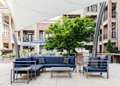 Thumbnail 25 of 36 - Outdoor sectional sofa seating under canopy at St. Marys Square Apartments, North Carolina