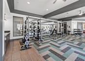 Thumbnail 23 of 31 - A gym with a variety of equipment including a squat rack, bench press, and a mirror at 1010 Dilworth Apartments, North Carolina