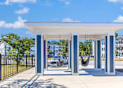 Thumbnail 12 of 21 - A white and blue structure with a hammock in front of a parking lot.