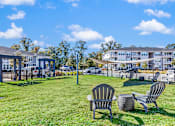 Thumbnail 11 of 21 - Two chairs and a table are on a lawn in front of a building.