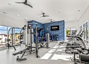 Thumbnail 14 of 21 - A gym with a row of treadmills and a blue wall with the word 