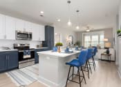 Thumbnail 1 of 15 - an open kitchen with an island and blue bar stools at Bristol at New Riverside, Bluffton