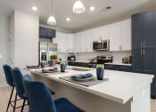 Thumbnail 2 of 15 - an open kitchen with a large island with blue chairs at Bristol at New Riverside, Bluffton South Carolina
