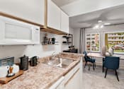 Thumbnail 11 of 23 - a kitchen with a sink and a microwave and a dining room at Falls Village Apartments, Maryland, 21209