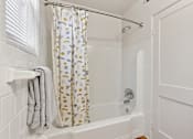 Thumbnail 6 of 19 - a bathroom with a shower curtain and a white tub at Donnybrook Apartments, Towson, 21286