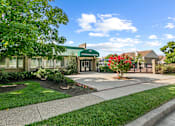 Thumbnail 19 of 20 - a green building with a sidewalk and trees in front of it at McDonogh Township Apartments, Owings Mills, MD