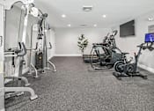 Thumbnail 16 of 20 - a gym with exercise equipment and a tv on the wall at McDonogh Township Apartments, Owings Mills