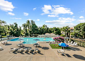Thumbnail 1 of 20 - a swimming pool with chairs and umbrellas at the resort at McDonogh Township Apartments, Maryland