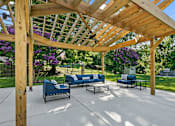 Thumbnail 3 of 20 - a covered patio with blue couches and a wooden pergola at McDonogh Township Apartments, Owings Mills