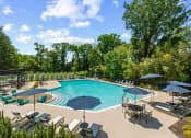 Thumbnail 17 of 31 - a swimming pool with umbrellas and chairs around it at Padonia Village Apartments, Timonium, 21093
