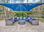 Thumbnail 30 of 42 - A patio with a blue canopy and grey wicker furniture at The Grand Reserve at Tampa Palms Apartments, Tampa, 33647