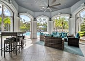 Thumbnail 31 of 42 - A patio with a table and chairs overlooking a pool at The Grand Reserve at Tampa Palms Apartments, Tampa