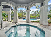 Thumbnail 28 of 42 - A pool surrounded by white columns and a white roof at The Grand Reserve at Tampa Palms Apartments, Florida