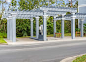 Thumbnail 40 of 42 - A grey pergola with columns and benches is situated on a paved car wash area at The Grand Reserve at Tampa Palms Apartments, Florida