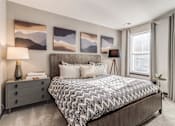 Thumbnail 4 of 18 - a bedroom with a bed and paintings on the wall at Dartmoor Place at Oxford Square Apartments, Hanover, Maryland
