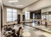 Thumbnail 13 of 18 - a workout room with bikes and a large screen on the wall at Dartmoor Place at Oxford Square Apartments, Hanover, MD