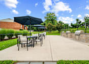 Thumbnail 20 of 26 - A patio with a table and chairs under an umbrella.