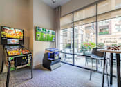 Thumbnail 18 of 26 - A room with a pinball machine and a TV showing a game at The Edison Lofts Apartments, Raleigh, NC