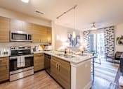 Thumbnail 1 of 26 - A modern kitchen with wooden cabinets and stainless steel appliances at The Edison Lofts Apartments, Raleigh, 27601