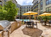 Thumbnail 10 of 21 - Grilling area with gas grills and patio seating with umbrellas at 1010 Dilworth Apartments, Charlotte North Carolina