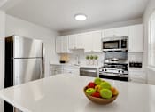 Thumbnail 1 of 35 - a kitchen with white cabinets and a bowl of fruit on the counter Kenilworth at Perring Park Apartments, Parkville, MD 21234