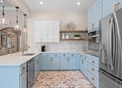 Thumbnail 30 of 33 - a kitchen with blue cabinets and a sink and a refrigerator at Sweetgrass Landing, Mount Pleasant, South Carolina