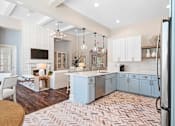 Thumbnail 31 of 33 - a kitchen with blue cabinets and a living room with a table and chairs at Sweetgrass Landing, South Carolina