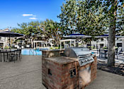 Thumbnail 24 of 33 - an outdoor patio with a barbecue grill and tables with umbrellas at Sweetgrass Landing, Mount Pleasant