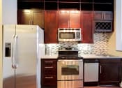 Thumbnail 30 of 64 - Kitchen with cherry oak cabinetry and stainless steel appliances at St. Mary's Square apartments, Raleigh, North Carolina