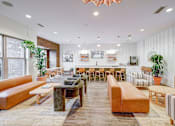 Thumbnail 14 of 16 - A modern resident clubroom with a variety of seating options and a long wooden table at The Linden Apartments, Davidson