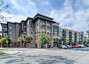 Thumbnail 16 of 16 - Apartment building exterior with cars parked in front at The Linden Apartments, Davidson, North Carolina