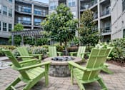 Thumbnail 9 of 16 - A fire pit surrounded by green chairs in a courtyard at The Linden Apartments, Davidson, 28036