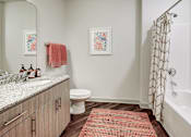 Thumbnail 7 of 16 - A bathroom with a toilet, sink, and shower at The Linden Apartments, North Carolina 28036