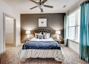 Thumbnail 6 of 16 - A bedroom with a bed, two lamps, and a ceiling fan at The Linden Apartments, Davidson, NC, 28036