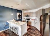 Thumbnail 2 of 16 - A kitchen with a white island and a stainless steel refrigerator at The Linden Apartments, North Carolina