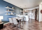 Thumbnail 1 of 16 - A kitchen with a table and chairs in front of a blue wall at The Linden Apartments, North Carolina