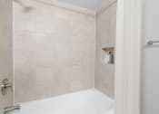 Thumbnail 6 of 31 - a bathroom with beige tiles and a white bathtub at Padonia Village Apartments, Timonium MD
