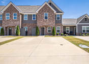 Thumbnail 2 of 29 - A large brick house with a driveway in front.