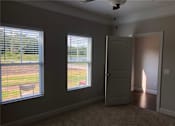 Thumbnail 34 of 47 - A room with a carpeted floor, a ceiling fan, and a door leading to a backyard.